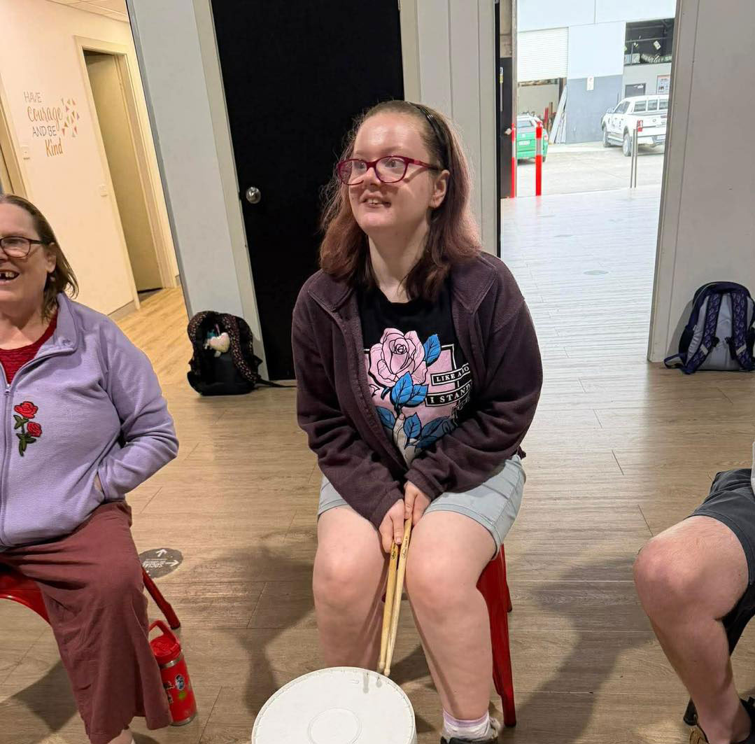 A Woman With Disability Holding Drum Sticks And White Bucket At The Front