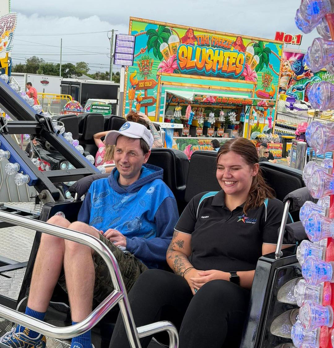 A Support Worker With A Disabled Person On A Ride On An Amusement Park
