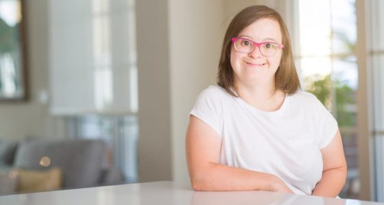 A Smiling Young Woman Sitting At A Desk — Gleam Support Services Pty Ltd in Weston, NSW
