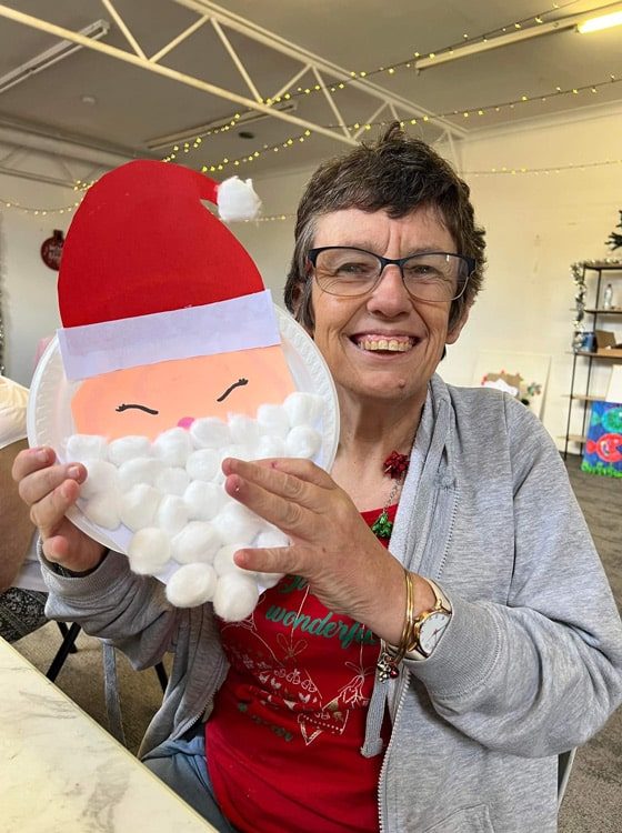 Woman Holding Santa Claus Art — Disability Services in Weston, NSW