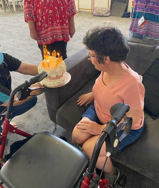 Woman Blowing Candle On Cake — Disability Services in Weston, NSW