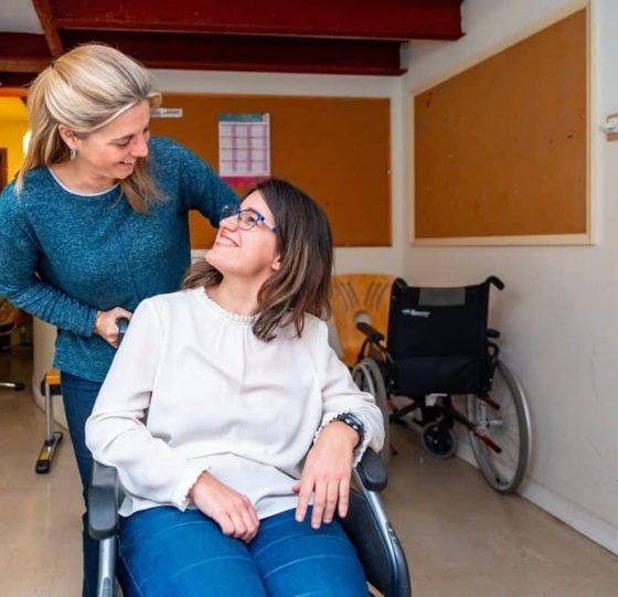Woman In A Wheelchair Receives Assistance From Another Woman, Showcasing Teamwork — Gleam Support Services Pty Ltd in Weston, NSW Woman In A Wheelchair Receives Assistance From Another Woman, Showcasing Teamwork — Gleam Support Services Pty Ltd in Weston, NSW