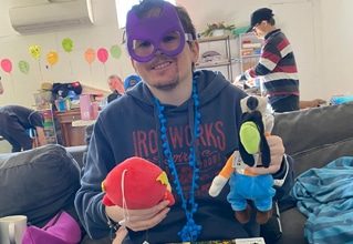Guy In Mask Holding Stuffed Toys — Disability Services in Weston, NSW