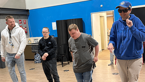 A Group of People Standing in A Room with A Man in A Blue Shirt — Disability Services in Cessnock, NSW