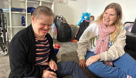 Two Women Sharing a Laugh While Seated on The Floor — Disability Services in Cessnock, NSW