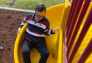 Man Playing In Slide — Disability Services in Weston, NSW