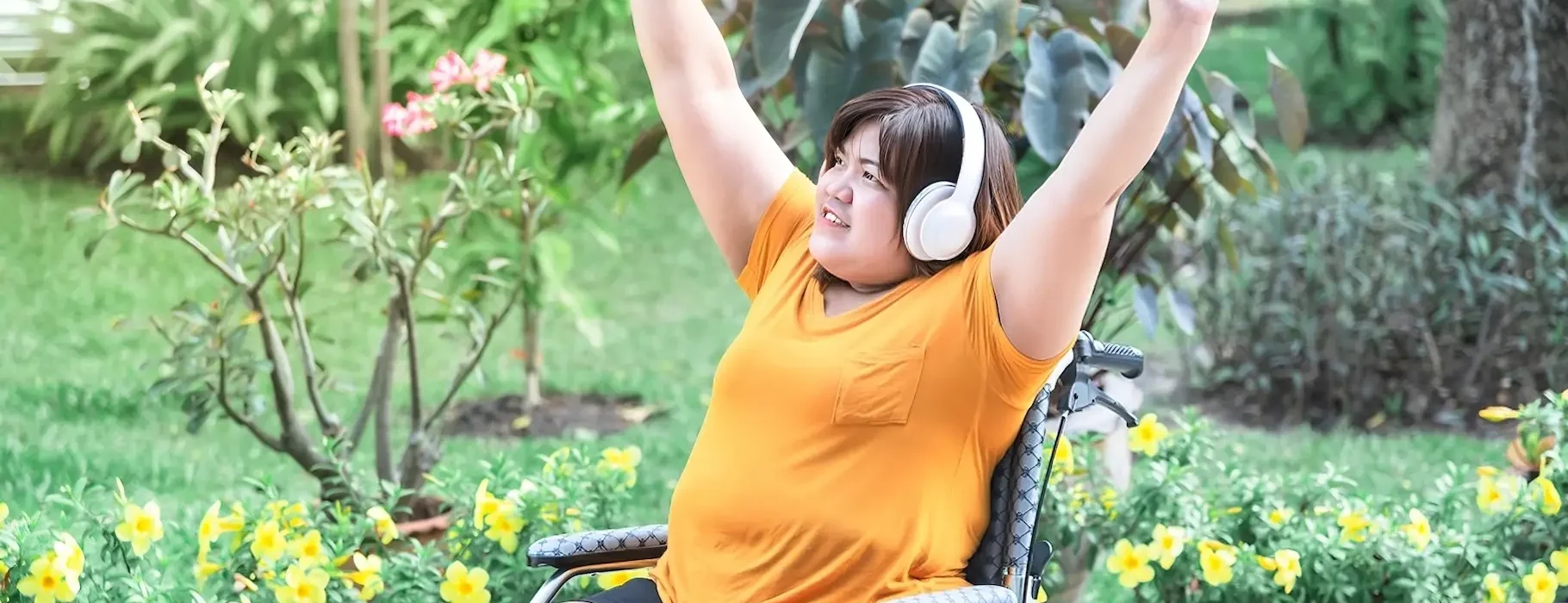 Woman In A Wheelchair Joyfully Raises Her Arms — Gleam Support Services Pty Ltd in Weston, NSW